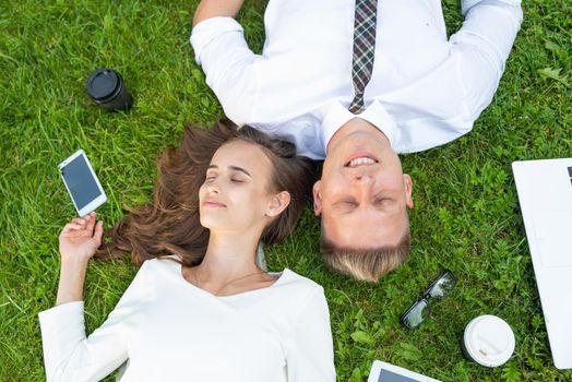 Business persons in the park sit on the grass in the park