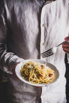 White plate with classic carbonara pasta in male hands