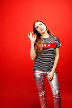 young pretty emitonal posing teenage girl on bright red background, happy smiling lifestyle people concept close up