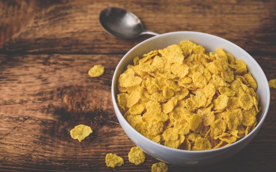 White bowl of corn flakes on a rustic wooden surface