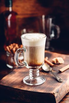 Coffee with Irish whiskey and whipped cream in glass on rustic wooden surface