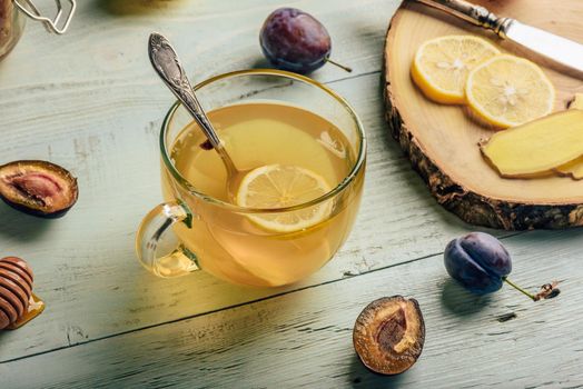 Cup of tea with lemon, honey and ginger over wooden surface