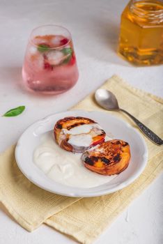 Served Grilled Peaches with Honey and Whipped Heavy Cream on White Plate and Glass of Raspberry, Mint Cocktail