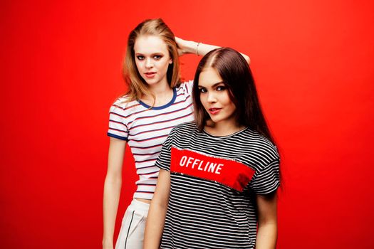 two best friends teenage girls together having fun, posing emotional on red background, besties happy smiling, lifestyle people concept close up