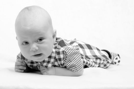 A charming baby lies on the blanket and looks into the camera. The concept of a happy childhood, the birth and upbringing of a child.