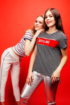 two best friends teenage girls together having fun, posing emotional on red background, besties happy smiling, lifestyle people concept close up