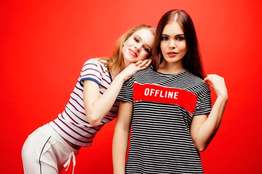 two best friends teenage girls together having fun, posing emotional on red background, besties happy smiling, lifestyle people concept close up