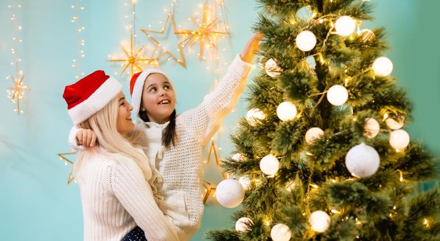 A young and happy mother and daughter in Christmas hats
