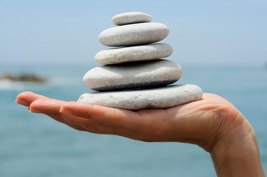 Close-up of gravel pile in woman's hands with sea background