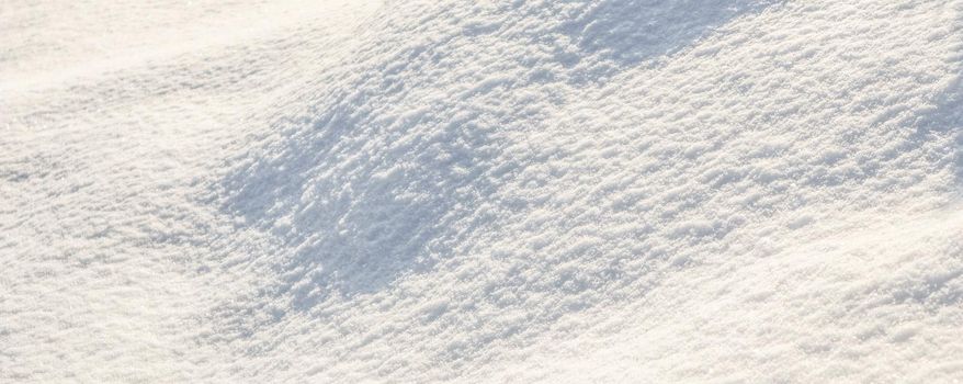 Hilly surface covered with fresh snow in the garden on a sunny day. Natural winter background.