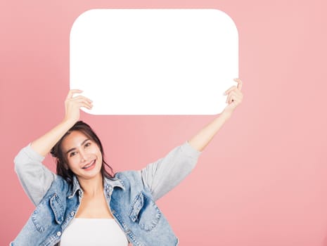 Happy Asian beautiful young woman smiling excited wear denims holding empty speech bubble sign, Portrait female posing show up for your idea looking at camera, studio shot isolated on pink background