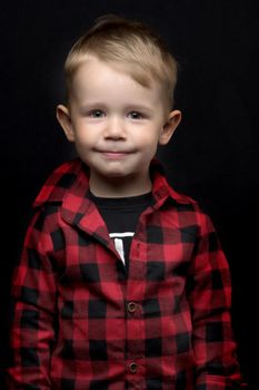 Cute little boy in studio on a black background. Concept Happy childhood, beauty and people.