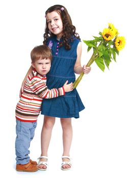 Little brother embracing his sister who is holding a bouquet of flowers.Isolated on white background portrait.