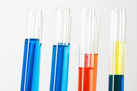 Laboratory analysis and testing. Close up test tubes with colorful reagents on white background. Scientific concept with glass chemical equipment. Pharmaceutical industry research and experiments