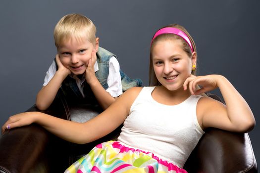 A teenage girl with her younger brother. studio photo session. The concept of family happiness.