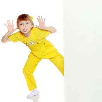 Girl with a short bangs on her head and bright yellow overalls.She crouched down on the white advertising banner.