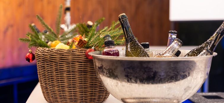 Wine in glass bottles is cooled in a metal bucket. Tasting of alcoholic beverages at the exhibition of winemakers. Christmas decor