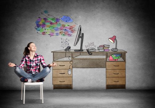 Young happy woman relaxing in room. Creative freelancer sitting in lotus pose on chair. Home workspace with computer on desk illustration on wall. Smiling girl doing yoga at home in leisure time.