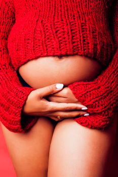 close up portrait of pregnant woman with big belly, hands hold, red sweater on background, choise of gender, lifestyle people concept