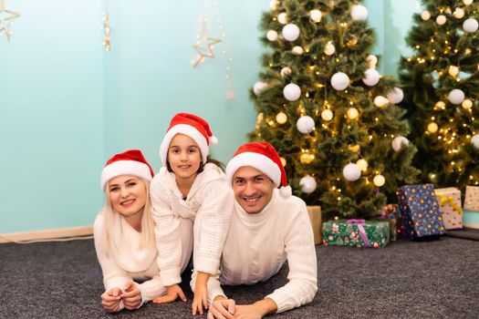 family, christmas, x-mas, winter, happiness and people concept - smiling family in santa helper hats with many gift boxes and bengal lights