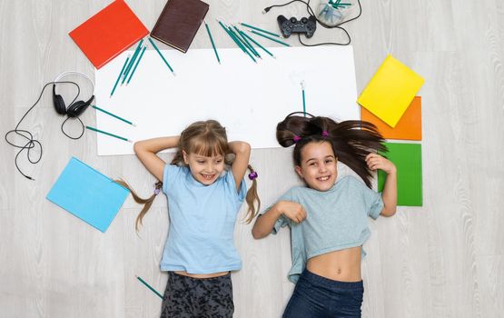 Cute children are painting and smiling while lying on the floor at home