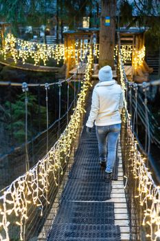 Winter lifestyle at Christmas. Caucasian woman on suspension bridge in garland Smiling with Christmas lights with a flaming torch and sparks.