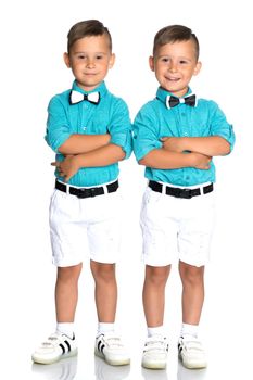 Two cute little boys stand in front of the camera in full growth. The concept of a happy childhood, the development of a child in the family. Isolated on white background.