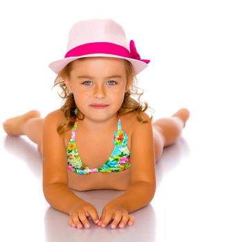 Beautiful little girl lies on the floor on a white background. The concept of a happy childhood, well-being in the family. Isolated.