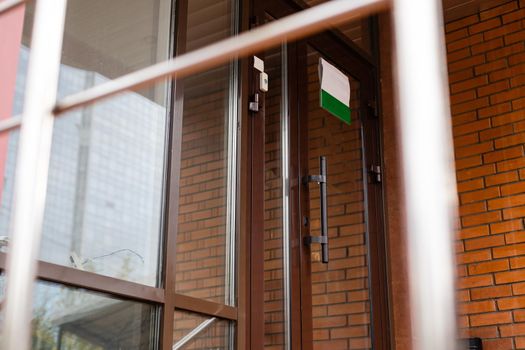 The front door of a office block, reflecting buildings in the glass.