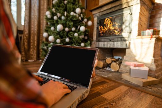 Happy woman looking in laptop in front of Christmas tree