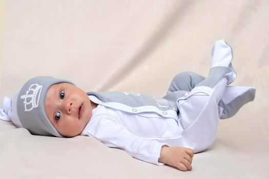 A charming baby lies on the blanket and looks into the camera. The concept of a happy childhood, the birth and upbringing of a child.