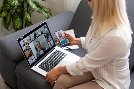 Back view of business woman talking to her colleagues about plan in video conference. Multiethnic business team using laptop for a online meeting in video call. Group of people smart working from home