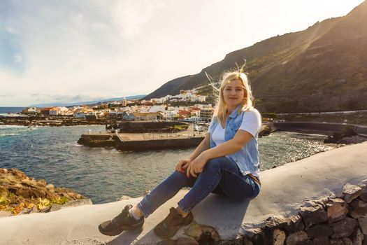 Young girl smiling and speaking consulting and giving instruction with voice recognition. Woman with audio recording in smart phone in the seaside in Garachico, Tenerife