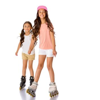 Two beautiful little Asian girls skate on roller skates. The concept of advertising sports goods, a healthy lifestyle, a happy childhood. Isolated on white background.
