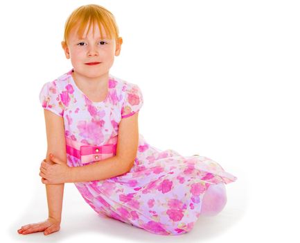 Sits leaning on hand a small charming girl. Isolated on white background