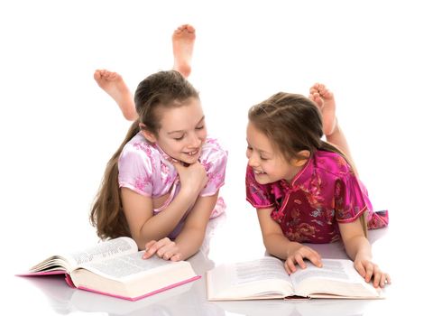 Lovely little girls are reading a book. The concept of education and education, family and people. Isolated on white background.