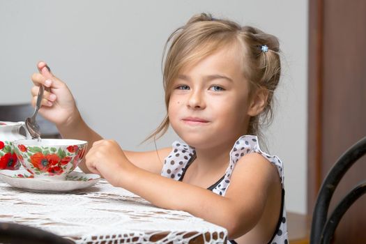 A little girl is drinking tea at the table. Stylized as a room of the fifties of last century. Retro style.