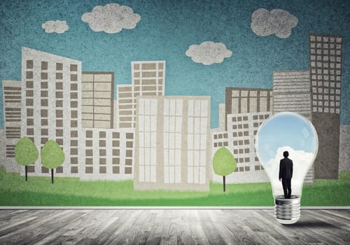 Businessman inside light bulb against city drawn concept