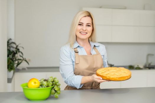Beautiful woman holding pie in the kitchen