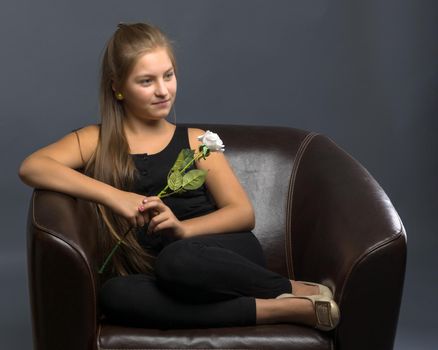 A teenage girl with a flower in her hand. Shooting in the studio on a black background.