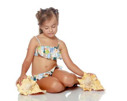 A little girl in a swimsuit with a shell. The concept of a family vacation at sea, a happy childhood. Isolated on white background.