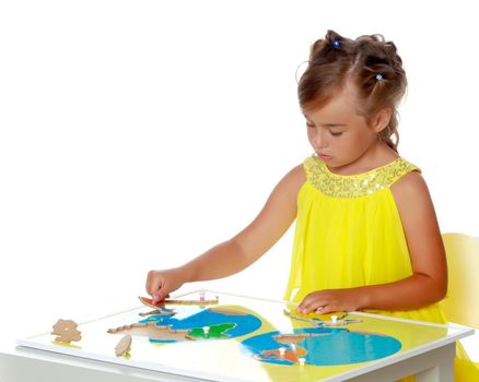 A little girl in Montessori kindergarten sits at a table and studies Montessori stuff. The concept of school and preschool education, harmonious development of the child. Isolated on white background.