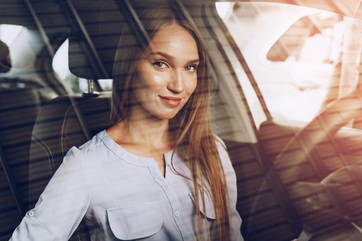 Attractive young woman sitting in new car in showroom close up