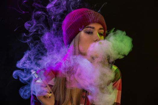 Vaping girl. Young hipster woman vape e-cig on studio on black background. Hip-hop style. Close up. Vapor concept. Vaping e-Cigarette.