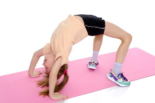 A little girl gymnast performs a bridge. The concept of childhood, sport, healthy lifestyle. Isolated on white background.