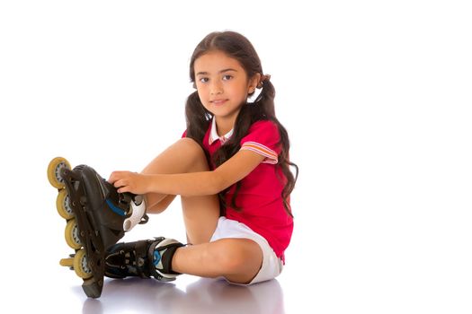 Beautiful little Asian girl puts on roller skates. The concept of advertising sports goods, a healthy lifestyle. Isolated on white background.