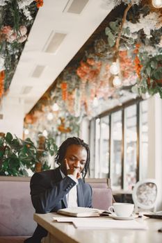 African man. Guy in a black suit. Male with a notebook.