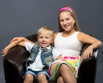 A teenage girl with her younger brother. studio photo session. The concept of family happiness.