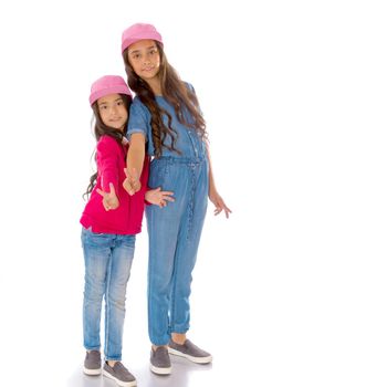 Two cheerful Asian girls show a gesture victoria. The concept of a happy childhood. Isolated on white background.