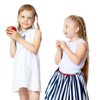 Two cute little girls with apples, in the studio on a white background. Concept of happy childhood, healthy eating. Isolated.